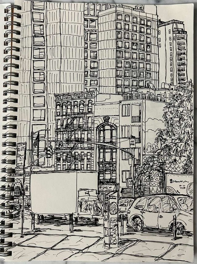 Dense pen drawing in a spiral sketchbook of New York's Lower East Side — tenement buildings, fire escapes, street trees and parked cars