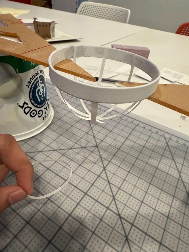 Hand holding the model's thin white dome ring above a cutting mat