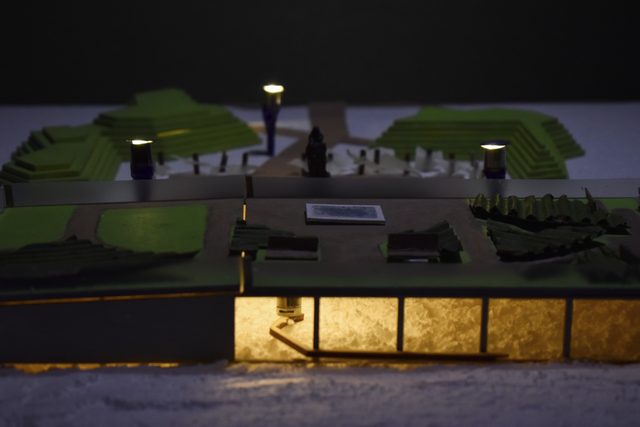 Close view of the model's illuminated glazed base beneath the dark landscape above