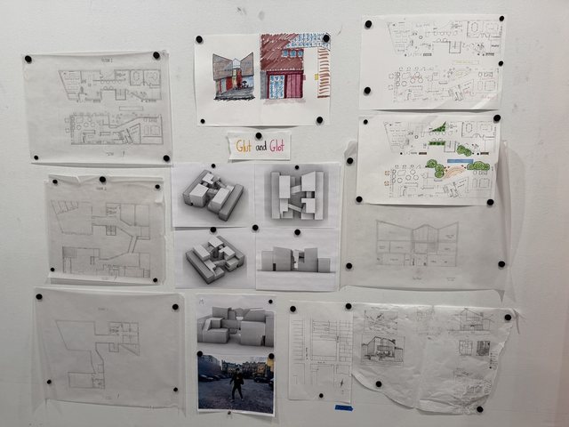 The project pinned up for review: plans, photographs of the model, collages and a hand-lettered sign